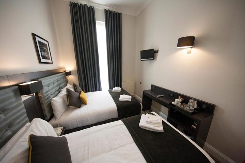 A triple room with one double bed and one single bed, desk and hospitality tray