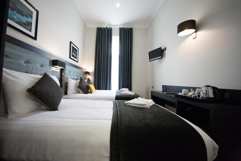 A triple room with one double bed in the foreground and one single bed beside the window