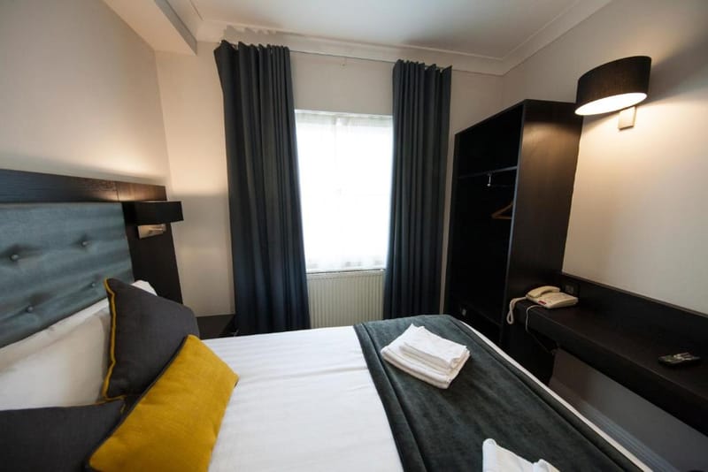 A double room with one double bed, a wardrobe and a tall sash window