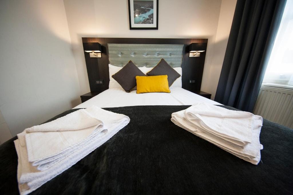 A double room with one double bed beneath a buttoned headboard, towels folded on the bed