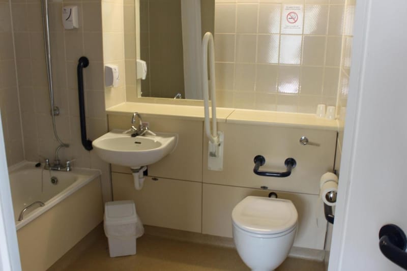 Bathroom with grab rails beside the basin and toilet