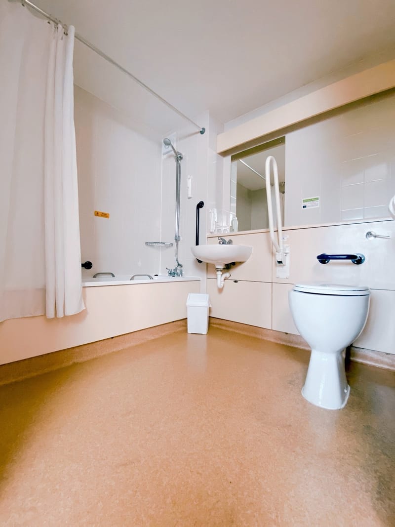 Adapted bathroom with grab rails and a bath with shower