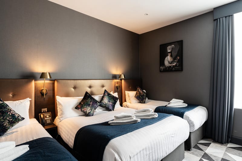 A quadruple room with a double bed and two singles, and a window onto the street