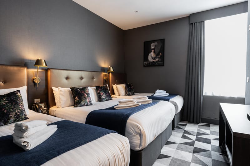 A quadruple room — a double bed and two singles on a chequerboard floor