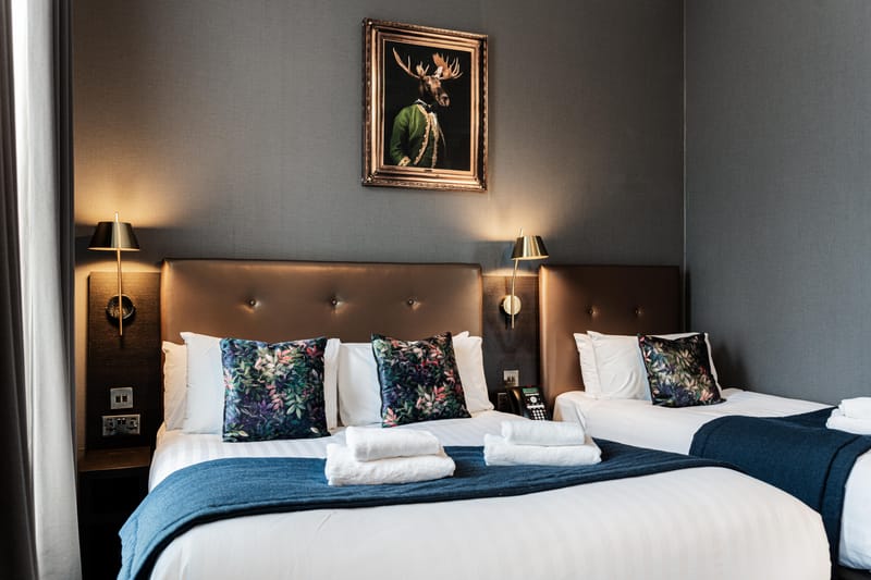 A triple room with a double bed and a single bed beneath a gilt-framed portrait
