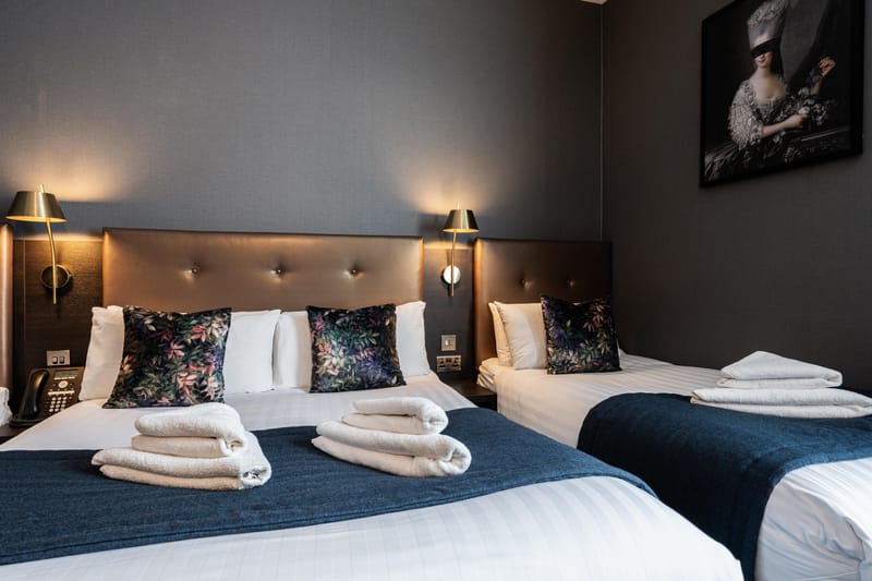 A triple room, a double bed and a single dressed in white linen and navy