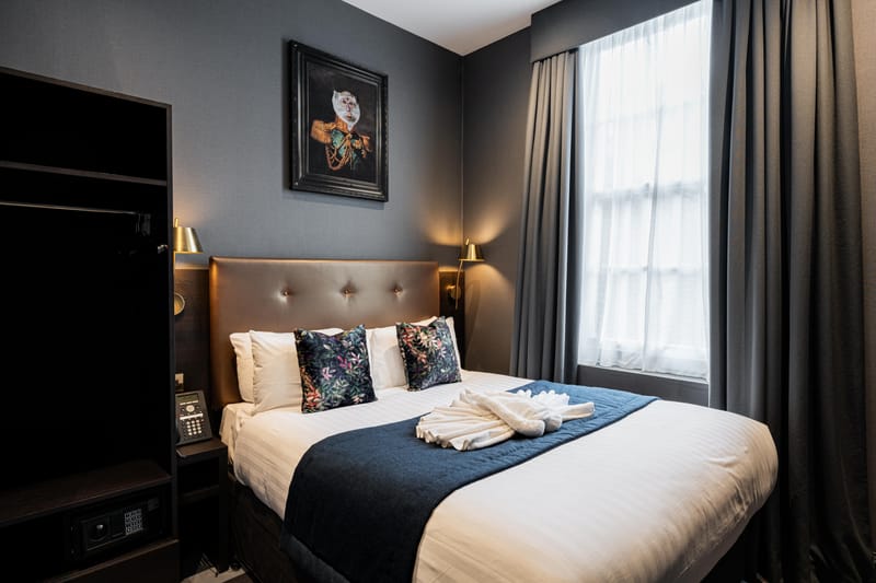 A double room with a window onto the street, a wardrobe and a wall-mounted television