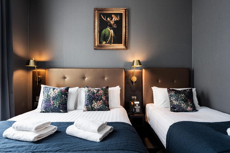 A triple room — a double bed and a single, beneath a gilt-framed stag portrait