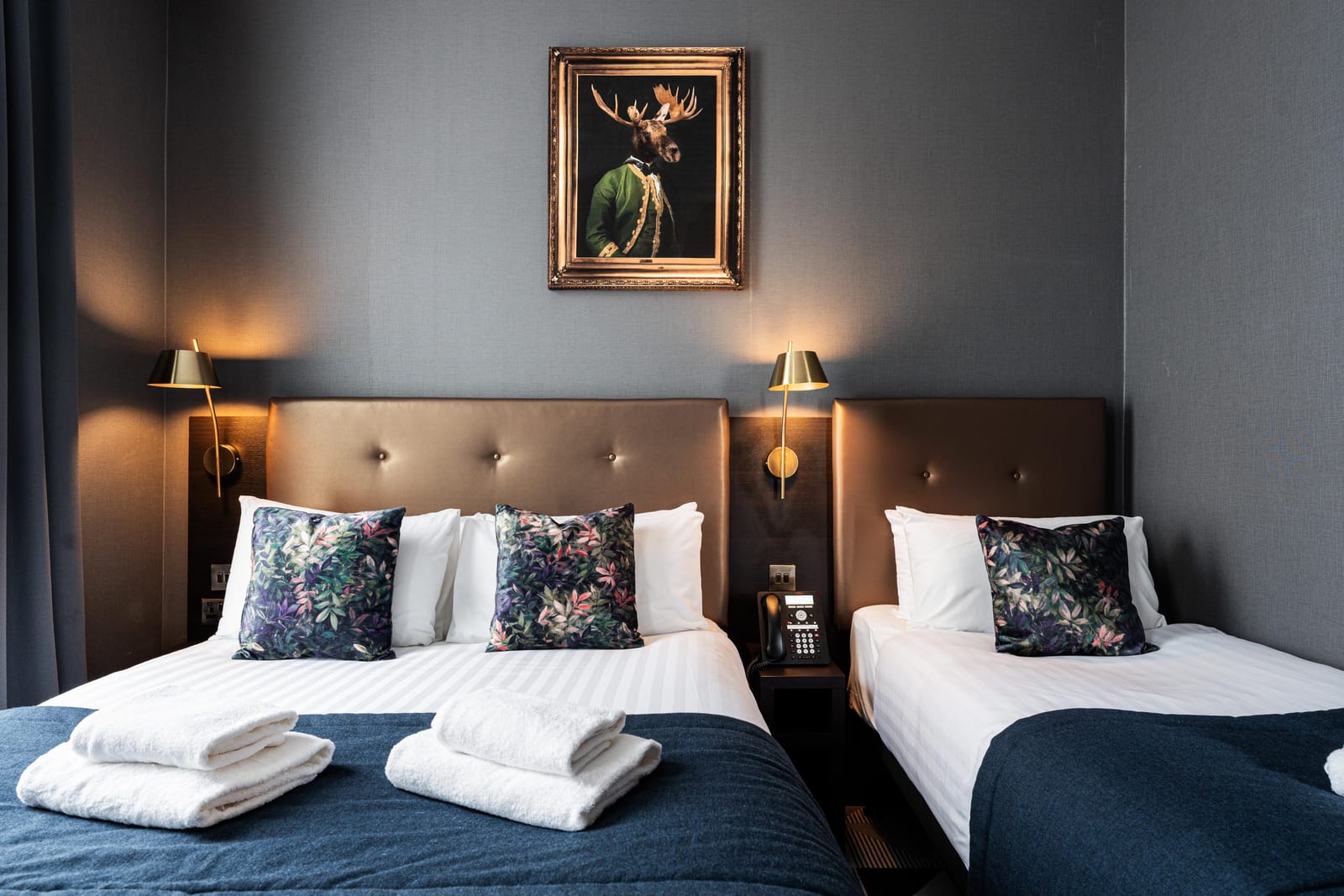 A triple room — a double bed and a single, beneath a gilt-framed stag portrait