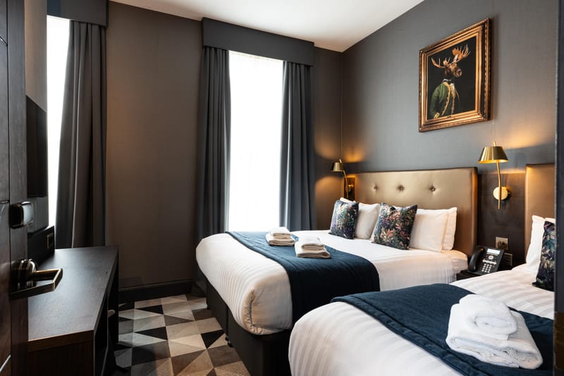 A triple room with a chequerboard floor, a double bed and a single by the window