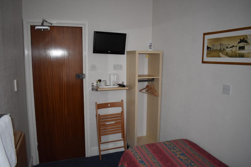 Single room with shared bathroom — door, television and shelf