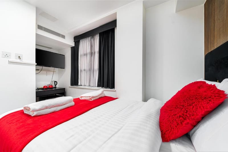 A Superior Double Room's double bed, made up in the hotel's red